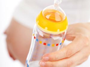 Mujer embarazada con biberón en la mano. / PublicDomainPictures (PIXABAY)